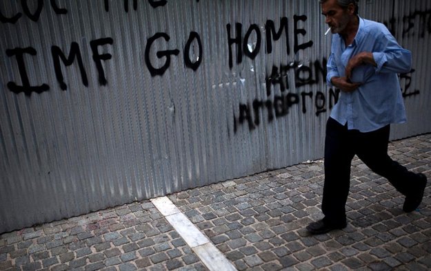 a man walks in front of graffiti reading 039 039 imf go home 039 039 in athens photo afp