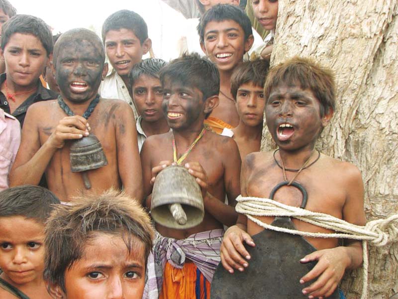 faces of orphans are blackened and an animal s bell and pan are tied around their necks photo gulsher panhwer