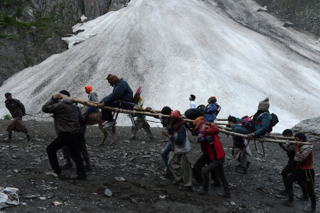 an indian hindu devotee is carried by kashmiri porters during the start of the annual journey from baltal base camp to the holy amarnath cave shrine in baltal near srinagar on july 2 2015 thousands of hindu pilgrims on july 2 2015 began trekking along icy trails to reach a cave shrine high in the mountains of india 039 s restive kashmir amid tight security photo afp
