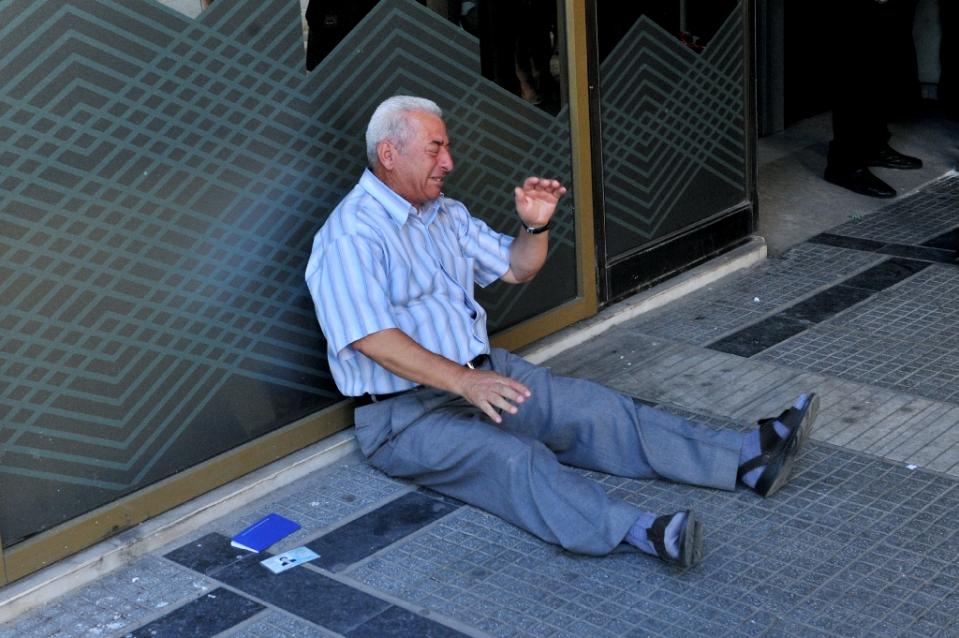 distressed greek pensioner giorgos chatzifotiadis sits on the ground outside a national bank branch in thessaloniki photo afp