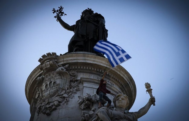 a person holds a greek national flag during a rally in support of the people of greece on the republique square statue at background in paris on july 5 2015 photo afp a person holds a greek national flag during a rally in support of the people of greece on the republique square statue at background in paris on july 5 2015 photo afp