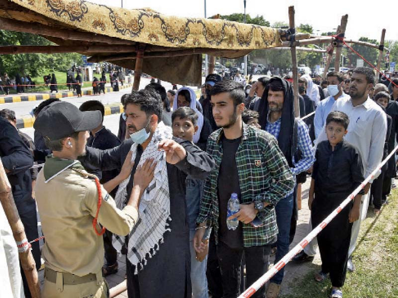 a boy scout stands guard at the entrance of an imambargah in the federal capital photo online