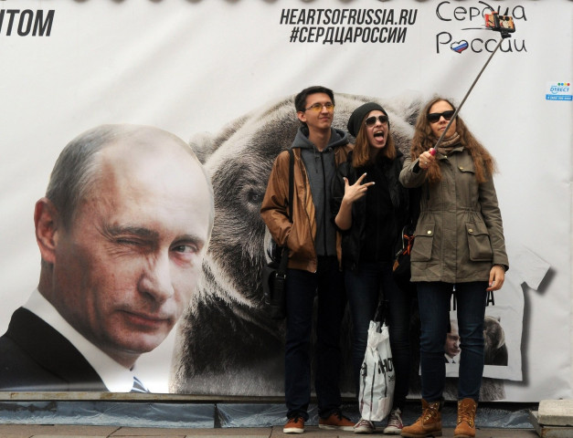a file picture taken on may 2 2015 shows people posing for a selfie photograph in front of a banner depicting russian president vladimir putin in st petersburg photo afp a file picture taken on may 2 2015 shows people posing for a selfie photograph in front of a banner depicting russian president vladimir putin in st petersburg photo afp