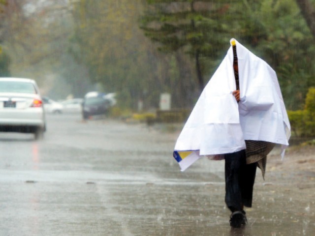 a man wraps himself with plastic sheeting as he walks during rain in islamabad photo afp