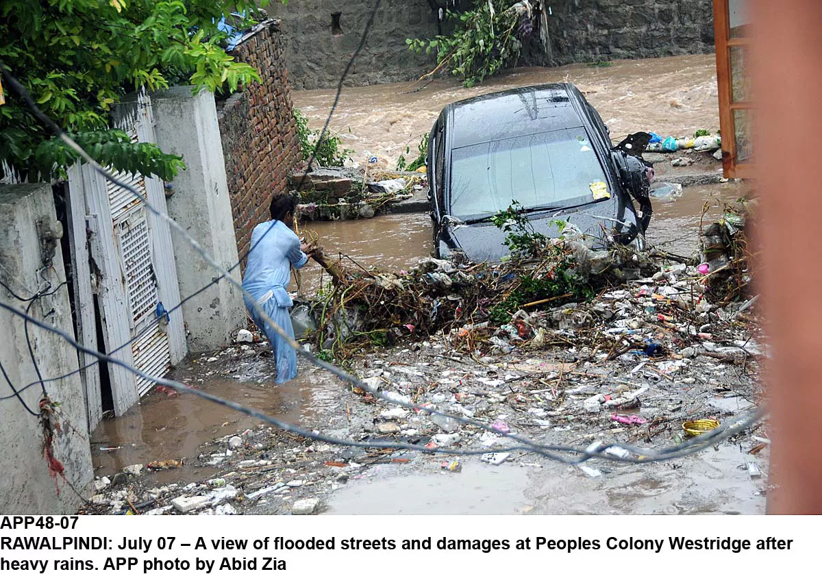 a man tries to clear debris in a rawalpindi street flooded with rain water photo app a man tries to clear debris in a rawalpindi street flooded with rain water photo app