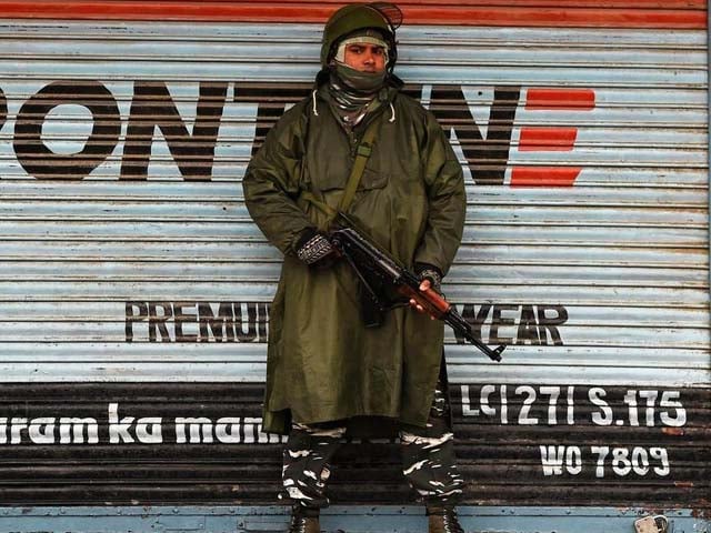 an indian paramilitary trooper stands guard in front of closed shops during a lock down in srinagar photo getty