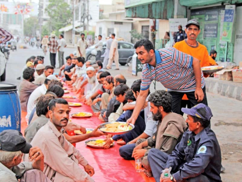 men take their seats at a dastarkhwan spread out on a footpath the number of people at these roadside iftars has soared due to poverty and inflation photo aysha saleem express