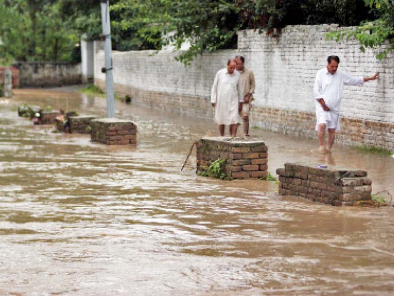 locals try to avoid walking in floodwater after heavy rains in abbottabad photo online