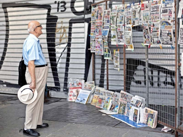 a man reads newspaper headlines at a newsstand in athens photo afp a man reads newspaper headlines at a newsstand in athens photo afp