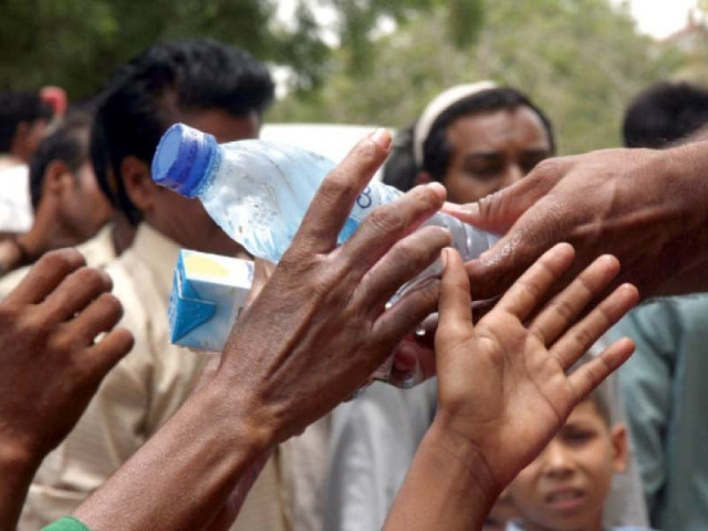 volunteers hand out water bottles and juice to people outside indus hospital during the recent heatwave that gripped the metropolis over 1 200 people died of heatstroke in the city photo file