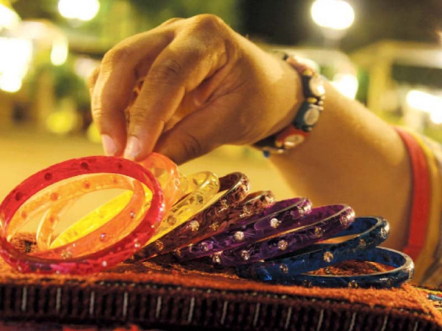 girls apply henna top left a couple chooses from a stall of embroidered items top a woman selects bangles at a stall at lok eid mela left photos huma choudhary express