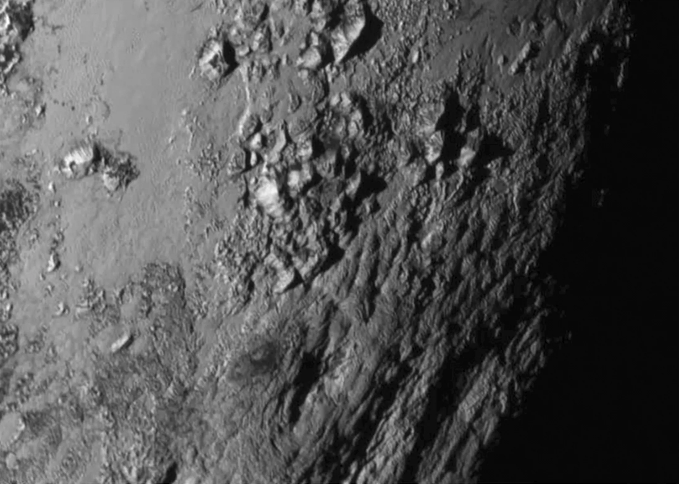 the first close up views of pluto show mountains made of ice and a surprisingly young crater free surface