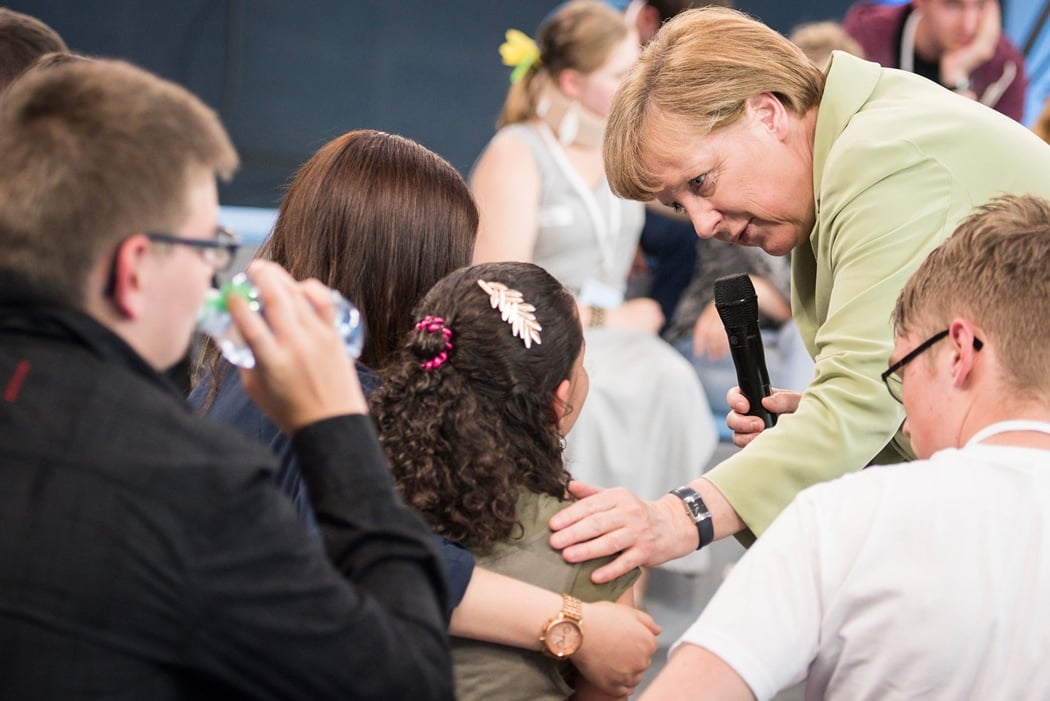 this handout photo made available by the german government press office on july 16 2015 shows german chancellor angela merkel r comforting a a crying palestinian girl threatened with deportation on july 15 2015 in rostock northern germany photo afp