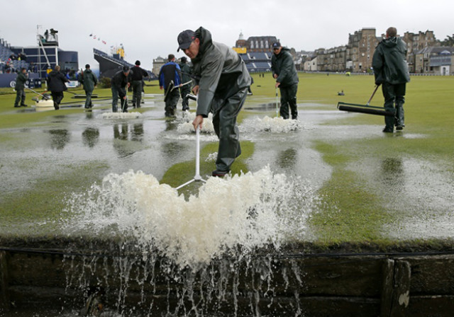 groundsmen sweep water into the swilcan burn after torrential rain made the old course unplayable on the second day of the british open golf championship photo afp groundsmen sweep water into the swilcan burn after torrential rain made the old course unplayable on the second day of the british open golf championship photo afp