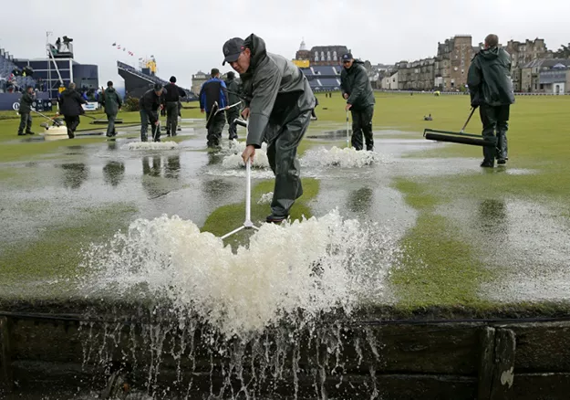 groundsmen sweep water into the swilcan burn after torrential rain made the old course unplayable on the second day of the british open golf championship photo afp groundsmen sweep water into the swilcan burn after torrential rain made the old course unplayable on the second day of the british open golf championship photo afp