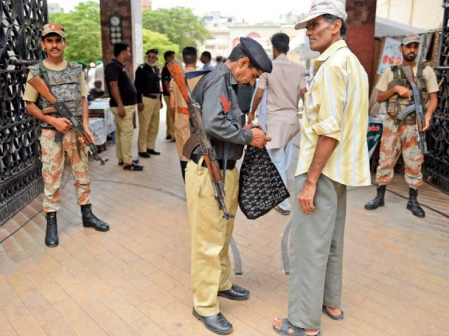 an officer goes through a man s belongings to ensure security on the last friday of ramazan strict security arrangements have been made for eidul fitr as well photo afp