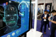visitors check their phones behind the screen advertising facial recognition software during global mobile internet conference gmic at the national convention in beijing china april 27 2018 photo reuters