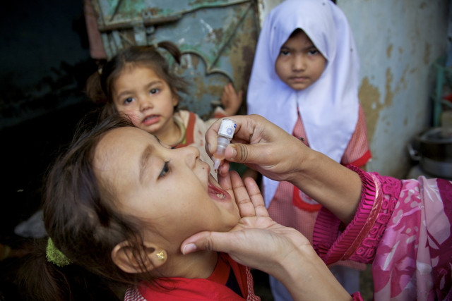 health worker vaccinating a child against polio outside her home during polio national immunization day nid while her sisters watching in sherpow in landhi town karachi pakistan photo cdc health worker vaccinating a child against polio outside her home during polio national immunization day nid while her sisters watching in sherpow in landhi town karachi pakistan photo cdc