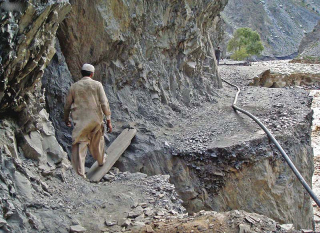 a man crosses a road damaged by floods in chitral photo inp a man crosses a road damaged by floods in chitral photo inp