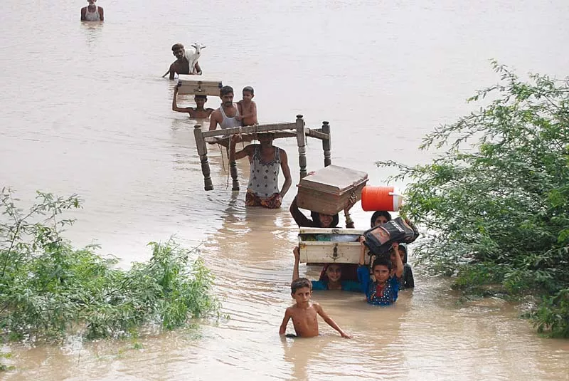 people wade through water carrying their essentials as a high flood passes through the barrages of sindh photo naeem ahmed ghouri express people wade through water carrying their essentials as a high flood passes through the barrages of sindh photo naeem ahmed ghouri express