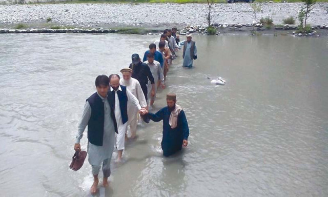 a man helps g b assembly deputy speaker jafarullah as he wades through floodwater in gilgit photo courtesy qasim shah a man helps g b assembly deputy speaker jafarullah as he wades through floodwater in gilgit photo courtesy qasim shah