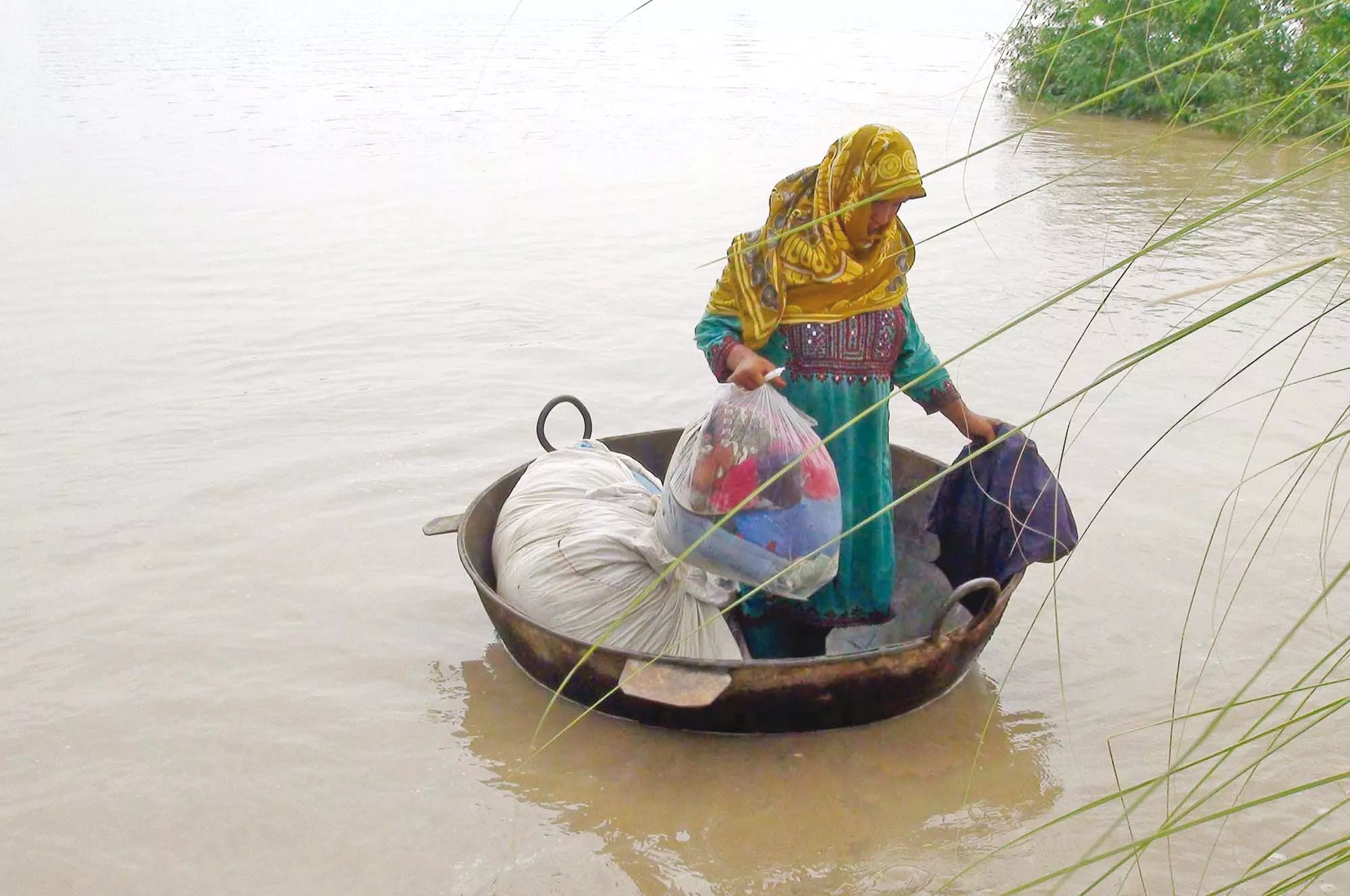 a woman uses a cauldron to reach dry land in a flood hit area of sukkur photo ppi a woman uses a cauldron to reach dry land in a flood hit area of sukkur photo ppi