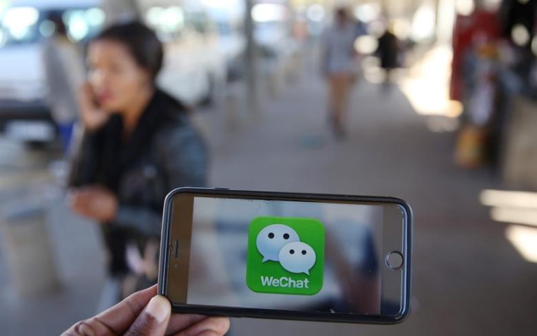 a wechat logo is displayed on a mobile phone as a woman walks past as she talks on her mobile phone at a taxi rank in this picture illustration taken july 21 2016 photo reuters