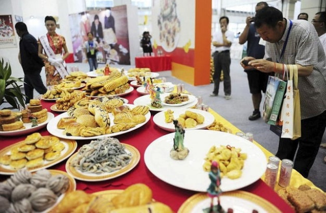 a visitor takes pictures at different types of food made of potatoes on display during the world potato congress on the outskirts of beijing china july 28 2015 photo reuters