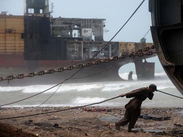 pakistani shipyard worker pulls on a wire attached to a motor that will help peel away part of the outer structure of a beached vessel photo getty