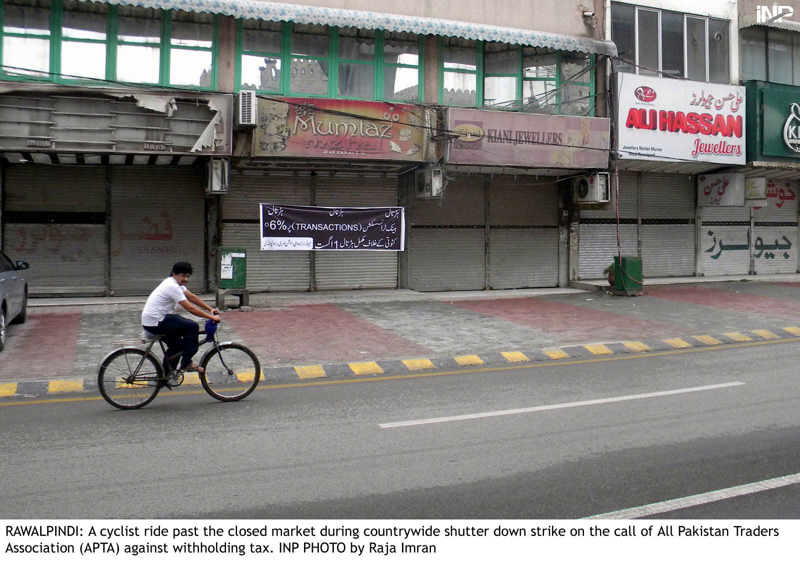 a man cycles past a closed market in rawalpindi as traders observed a strike against government 039 s decision to impose withholding tax photo inp