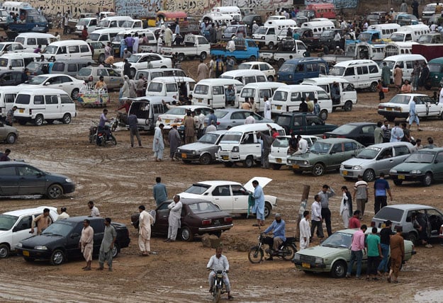 in this photograph taken on july 26 2015 people gather around cars at the sunday car market in karachi photo afp