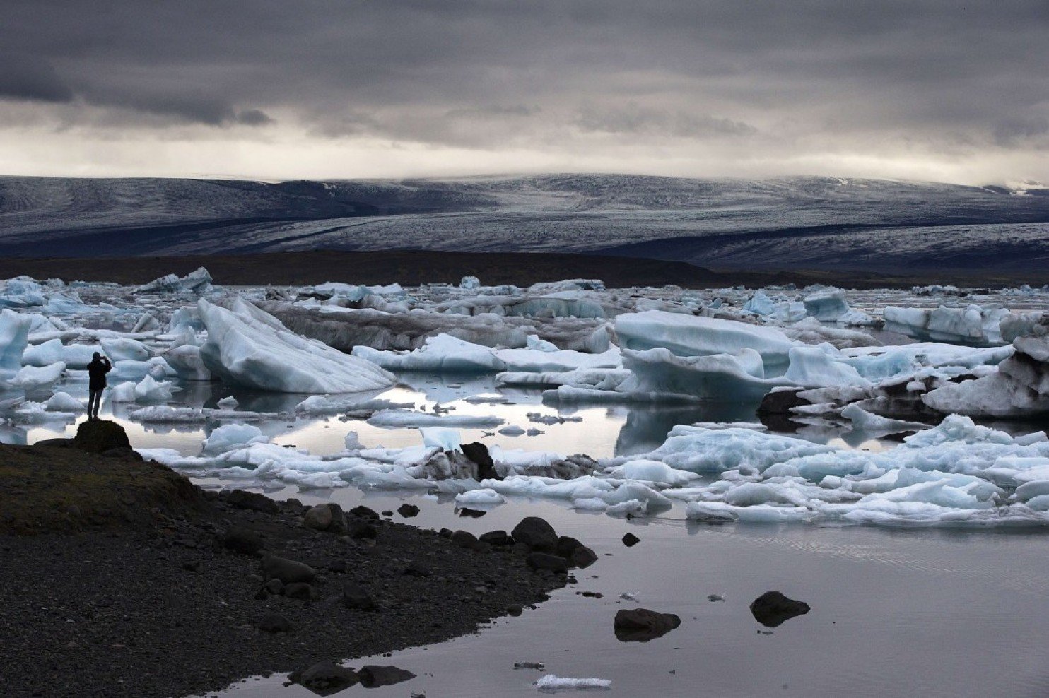 a man takes a picture of blue icebergs in jokulsarlon iceland the largest glacier lagoon in the nation on july 8 2014 photo afp