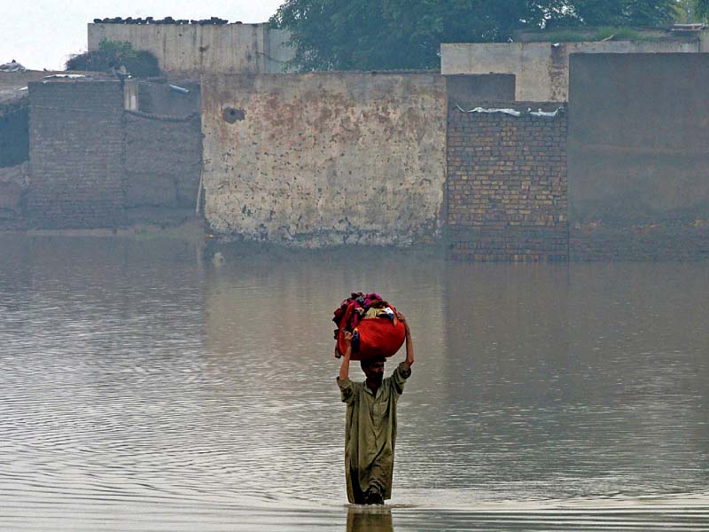 a man carries his belongings as he wades through a flooded area in nowshera district of khyber pakhtunkhwa photo afp