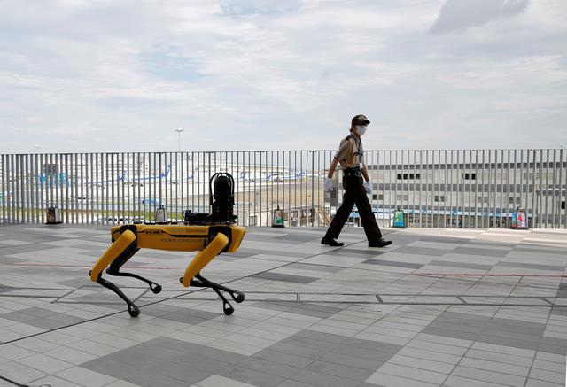 a security guard walks alongside boston dynamics four legged robot spot during its demonstration at tokyo robot collection japan september 18 2020 photo reuters