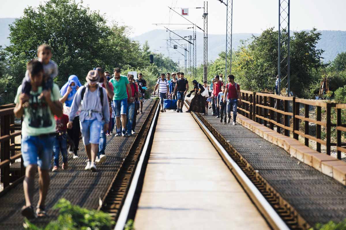 migrants walk on train tracks towards the town of gevgelija on the macedonian greek border on august 4 2015 at the train station of gevgelija on the macedonian greek border on august 4 2015 photo afp