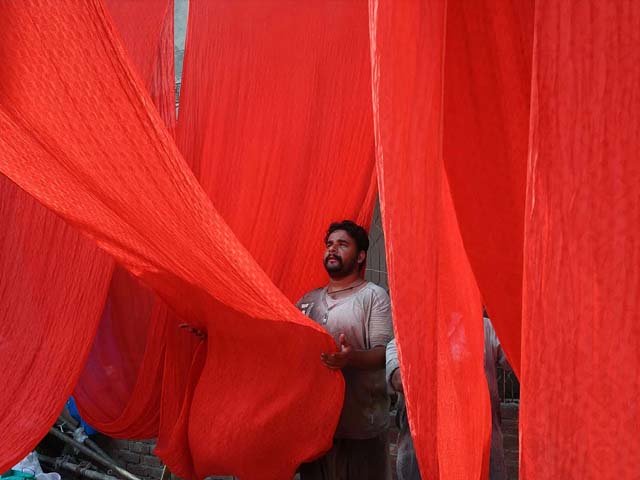 a labourer hangs fabrics to dry after a dyeing process in lahore photo getty