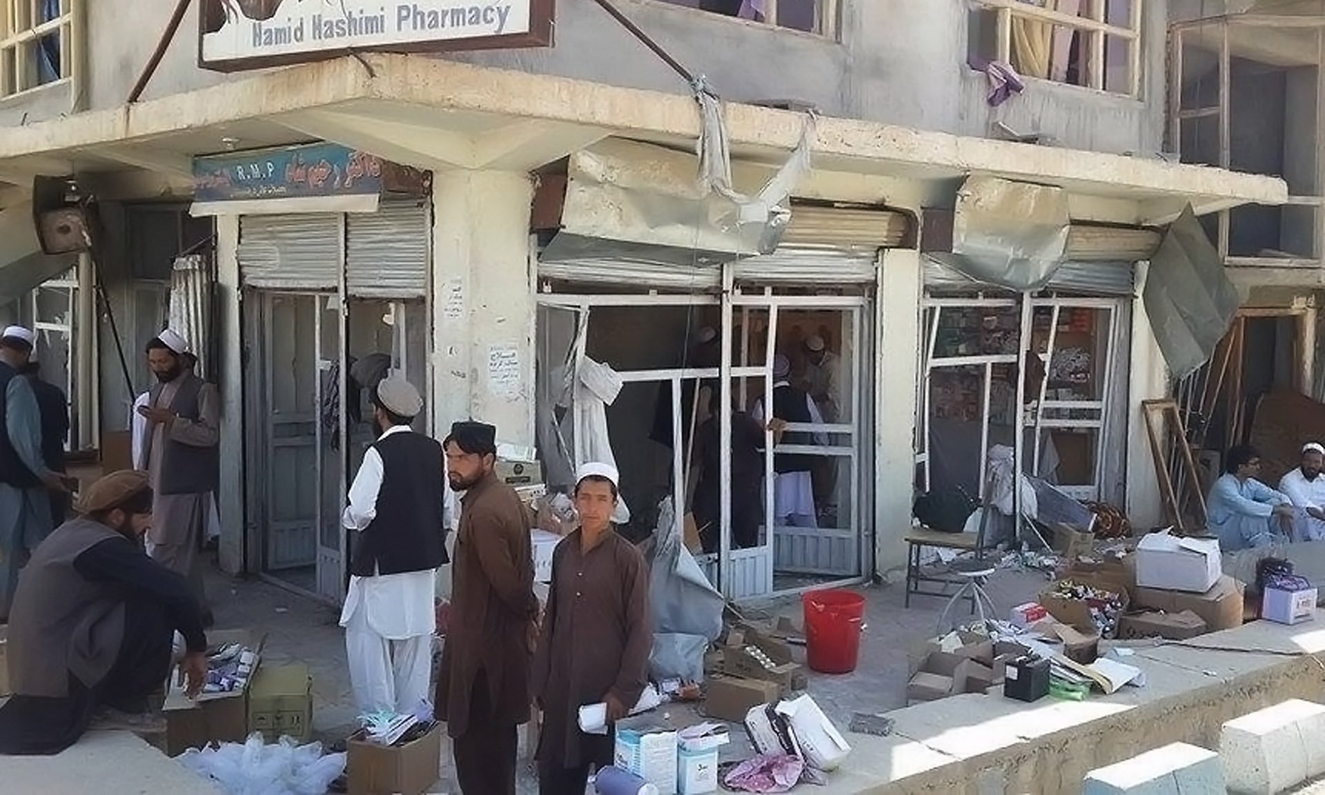 afghan shopkeepers sweep broken glass and debris at the site of a blast in pul i alam photo afp