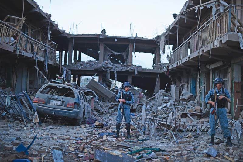 afghan policemen stand guard at a market destroyed by a powerful truck bomb in kabul photo afp