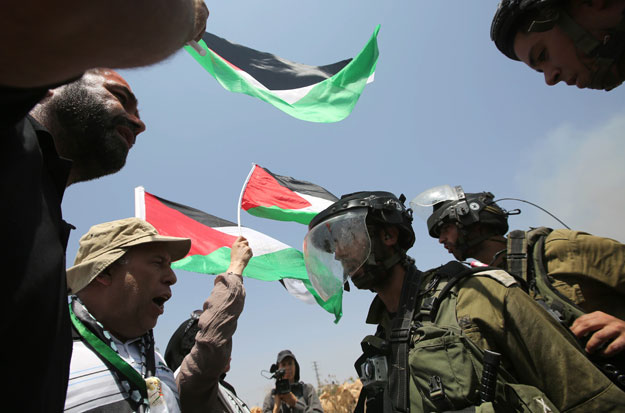 palestinian protester waving the national flag confront israeli security forces during clashes following a demonstration against the death of a 18 month old child killed in an arson attack in the occupied west bank earlier in the week on august 7 2015 in the west bank village of nabi saleh located near ramallah photo afp