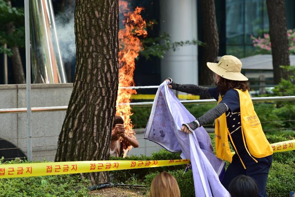 a man sets himself on fire as a south korean woman tries to extinguish the flames outside the japanese embassy in seoul photo afp