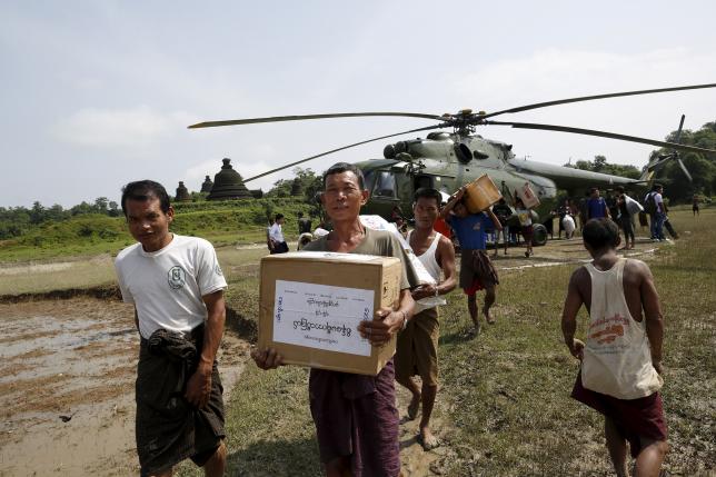 storm victims carry aid from a military helicopter at mrauk u township rakhine state photo reuters