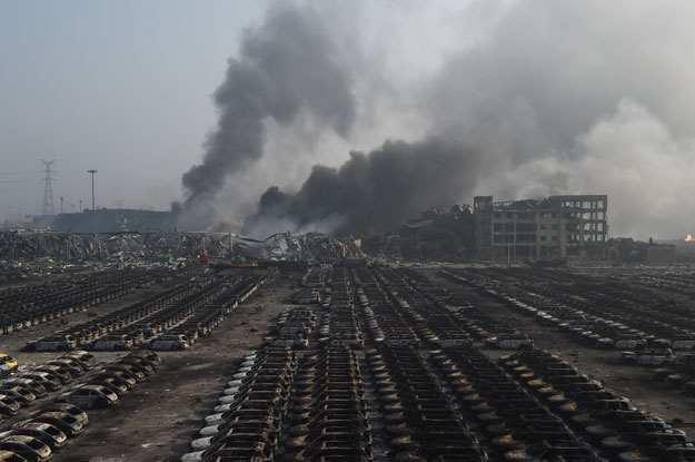 smoke billows behind rows of burnt out volkswagen cars at the site of a series of explosions in tianjin northern china on august 13 2015 photo afp