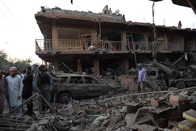 residents walk at a market destroyed by a powerful truck bomb in kabul on august 7 2015 photo afp