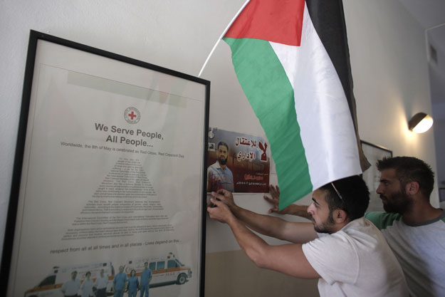 palestinians occupy the red cross headquarters in east jerusalem on august 16 2015 in solidarity with 31 year old mohammed allan portrait a palestinian held by israel without trial and who has reportedly slipped into a coma after a nearly two month hunger strike photo afp