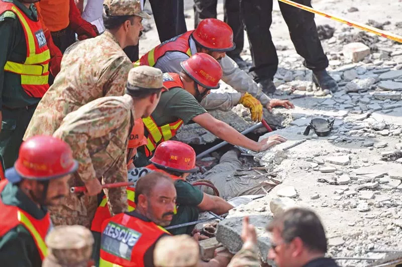 rescuers scramble to retrieve the body of a victim from underneath the rubble of col khanzada s residence after a suicide blast in attock photo afp rescuers scramble to retrieve the body of a victim from underneath the rubble of col khanzada s residence after a suicide blast in attock photo afp