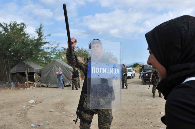 a migrant girlclashes with a macedonian police officer near the town of idomeni northern greece on august 21 2015 photo afp a migrant girlclashes with a macedonian police officer near the town of idomeni northern greece on august 21 2015 photo afp