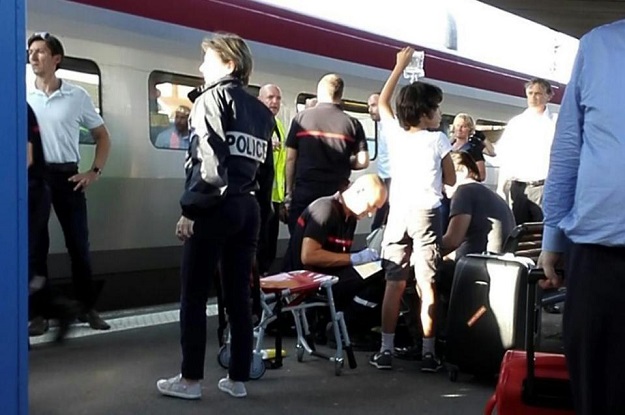 a police officer stands by as a passenger receives medical attention in arras northern france after being injured on august 21 2015 when a gunman opened fire on a train photo afp