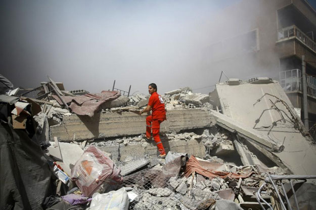 a member of the syrian red crescent inspects rubble searching for victims in the rebel held area of douma following shelling and air raids by syrian government forces on august 22 2015 photo afp