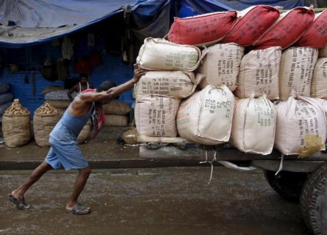 a labourer pushes a handcart loaded with sacks containing tea packets towards a supply truck at a wholesale market in kolkata june 26 2015 photo reuters
