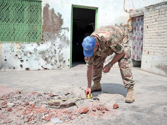 a unmogip member inspects a house damaged in indian shelling photo afp a unmogip member inspects a house damaged in indian shelling photo afp